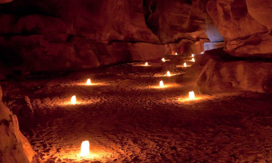 Empty candle lit path through a cave.